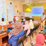 موظف يعرض شرائح عن التوعية بالمخاطر أمام مجموعة جالسة في قاعة اجتماعات جدرانها مغطاة بالخرائط