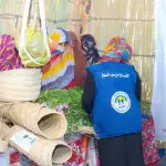 موظفة من المنظمة بصديرية جينز ترتّب خضاراً طازجة في ركن تُعرض فيه سلال مصنوعة من السعف
