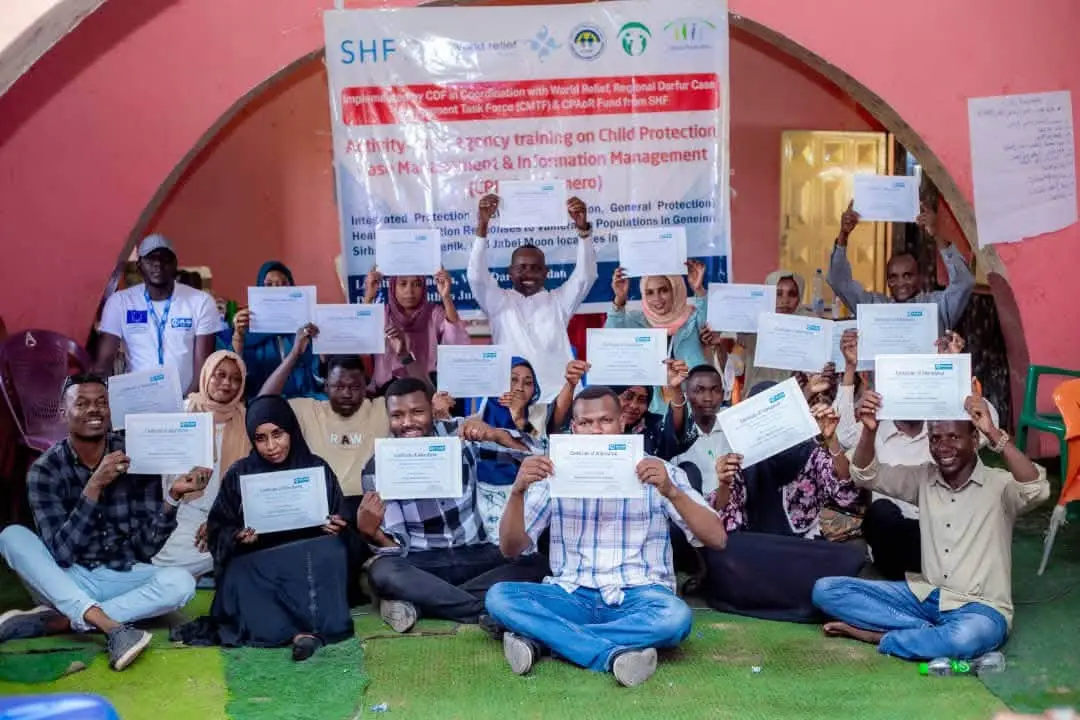 Trainees hold up their certificates after child protection case management training in El Geneina